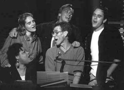 A picture of Steve Schalchlin playing piano and singing, surrounded by four other cast members who are also singing.
He is visibly thin but was beginning to put on weight
again.